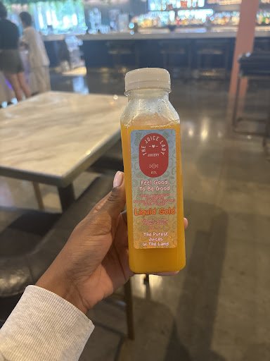 A customer holding a Liquid Gold juice bottle from The Juice Lady ATL